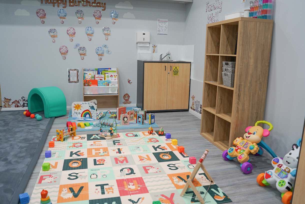 The Honeysuckles room, with an alphabet play mat, a book stand and a soft climbing tunnel.